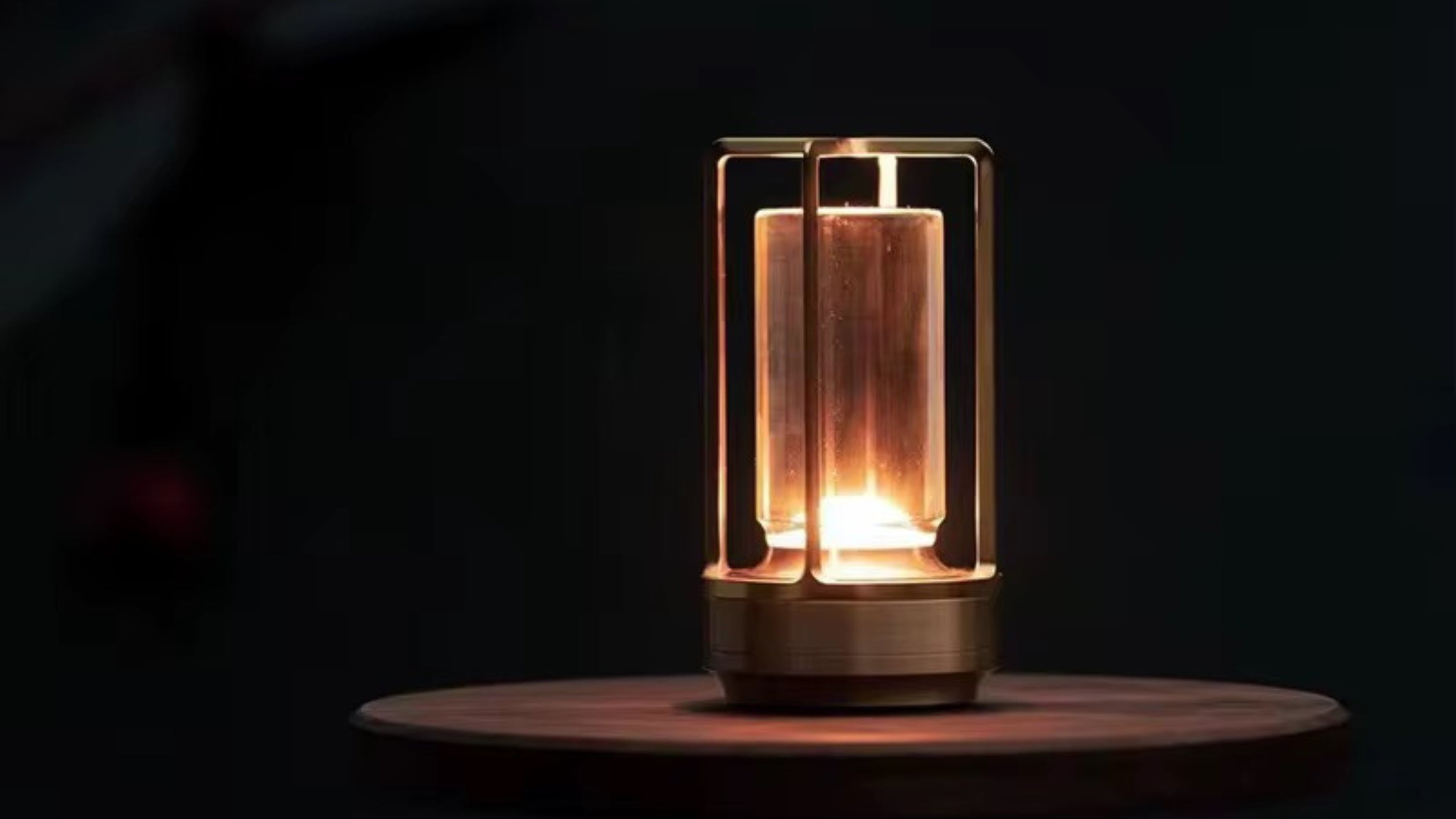 Ein warm leuchtendes Ambient Light auf einem Glastisch neben einem Whiskeyglas, im Hintergrund ein Sofa mit Decke – gemütliche Abendstimmung