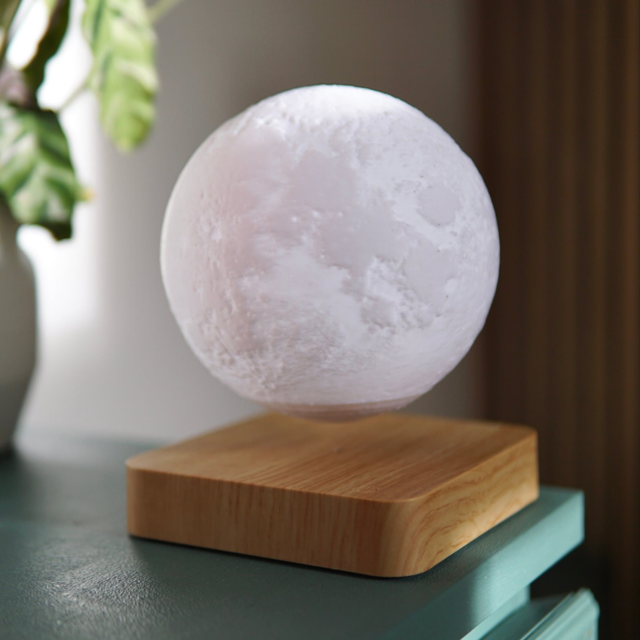 Levitierende Mondlampe bei Tageslicht mit naturgetreuem Kraterdesign auf Holzsockel