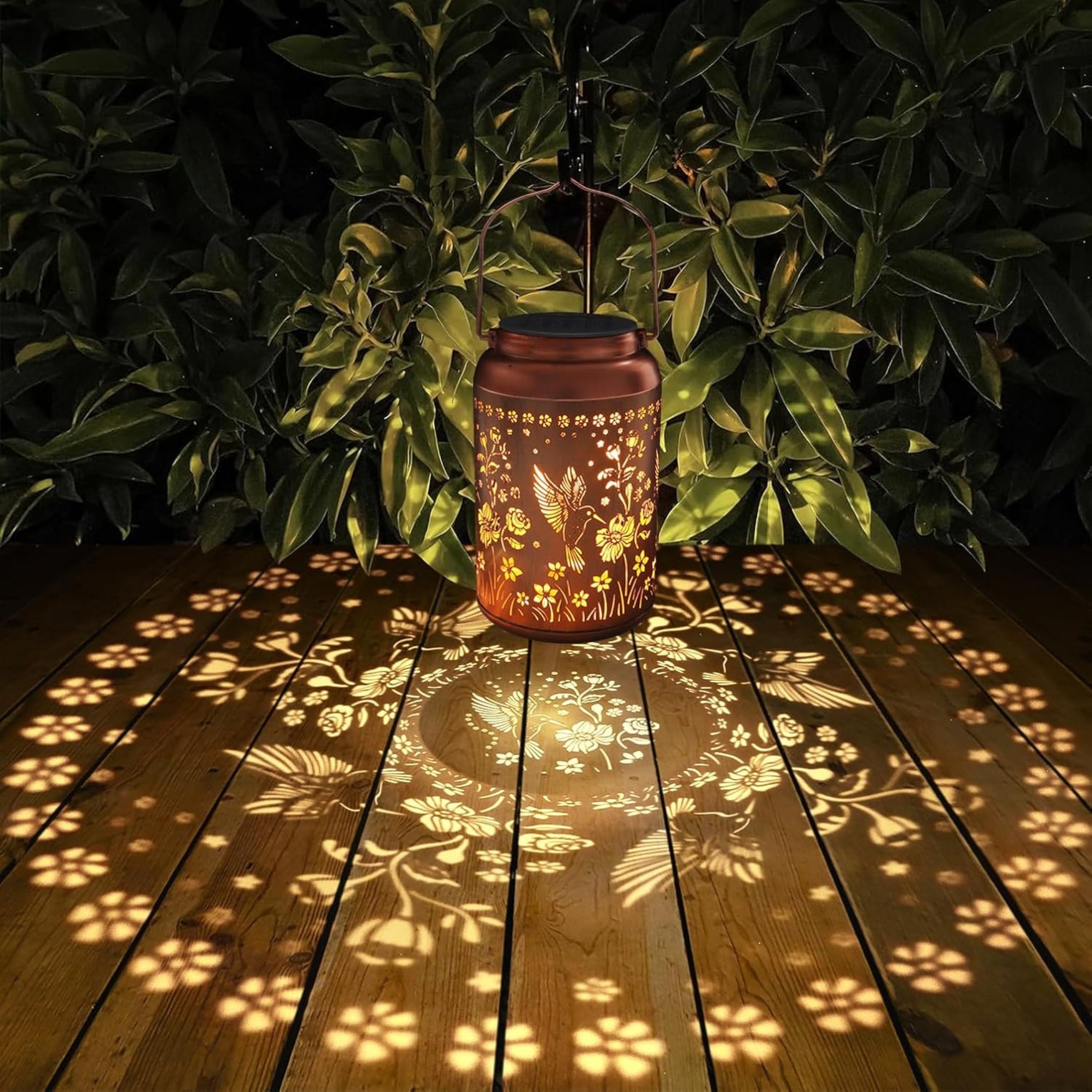 Soluna Laterne auf Holzterrasse mit floralen Lichtreflexionen bei Nacht